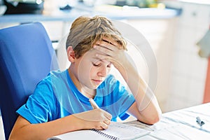 Young boy doing his homework at home. School kid learning