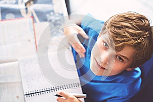 Young boy doing his homework at home. School kid learning.