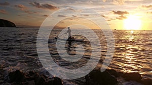 Young boy doing paddle surf at sunset