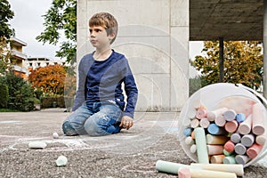 Young boy drawing on the sidewalk with chalk