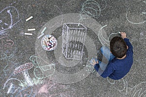 Young boy drawing on the sidewalk with chalk photo