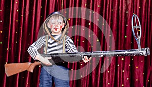 Young Boy Dressed as Clown Holding Oversized Rifle