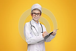 Young Boy Dressed as Doctor With Clipboard on Yellow Background