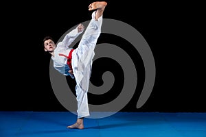 Young boy dressed in a white karate kimono with red belt.