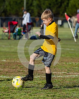 Young boy dribbles soccer ball during game