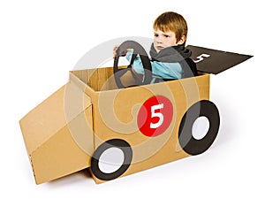 Young boy driving his cardboard car