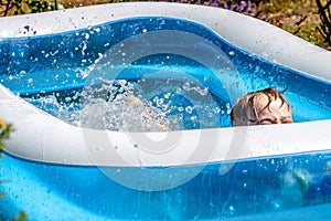 Young boy drowning in the swimming pool in the summer