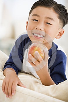 Young boy eating apple in living room