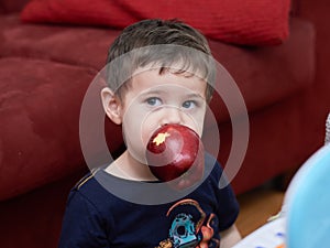 young boy eating an apple in the livingroom