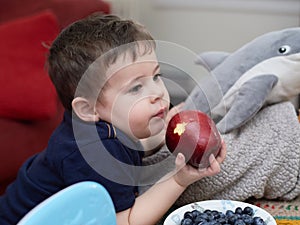 young boy eating an apple in the livingroom