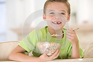 Young boy eating cereal in living room smiling