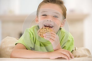 Young boy eating cookie in living room smiling