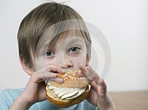 Young boy eating a cream bun