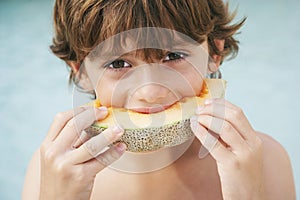 Young Boy Eating Slice Of Melon