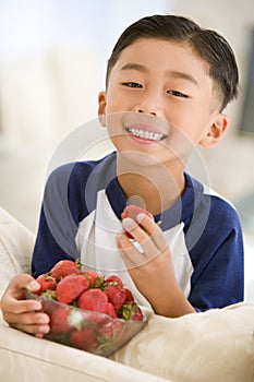 Young boy eating strawberries in living room