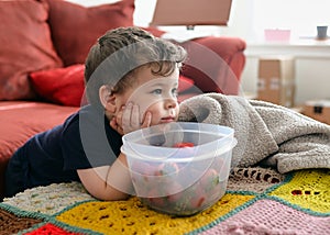 young boy is eating strawberries while watching TV