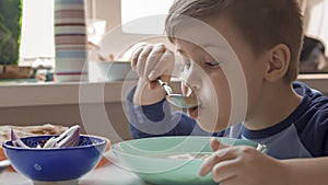 Young Boy Eats Soup Sitting At Dining Room Table