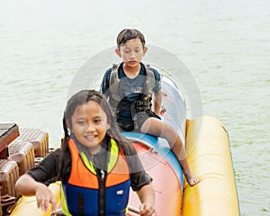 Young boy enjoying water activities on banana boat at the Kenyir Lake, Terengganu, Malaysia