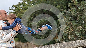 A young boy excitedly jumping from a rock into his father's arms