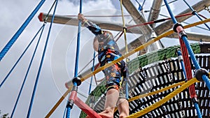 Young boy exploring a climbing frame rope ladder