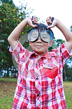 Young boy exploring nature with magnifying glass. Outdoors.