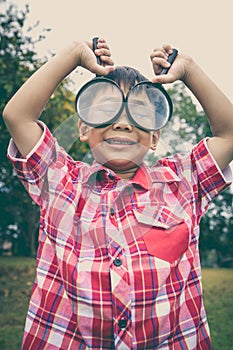 Young boy exploring nature with magnifying glass. Outdoors.