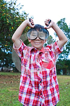 Young boy exploring nature with magnifying glass. Outdoors.