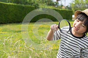 Young boy exploring nature in the meadow with a magnifying glass looking at flowers. Curious children in the woods, a future botan