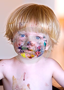 Young boy with face covered in colourful paint