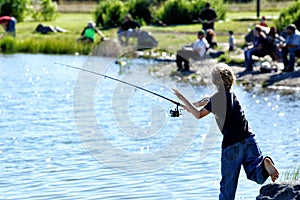 A young boy fishes at a fishing pond.