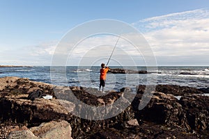 A young boy fishes in the sea in Fife, Scotland photo