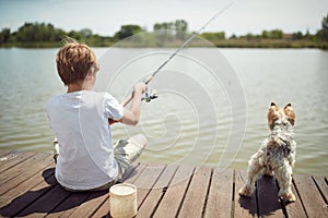 Young boy fishing on a lake with his dog