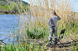 Young boy fishing on a lake shore