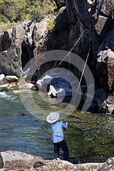 Young Boy Flyfishing in Rocky Alcove in Yellowstone National Park photo