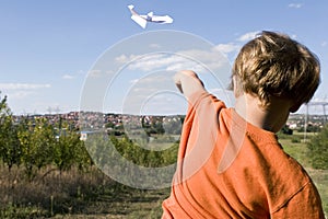 Young boy flying a paper plane