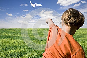 Young boy flying a paper plane