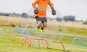 Young boy football soccer goalie on training session jumping high over hurdles