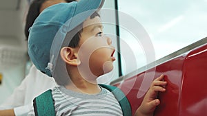 A young boy gazes out a train window, curiosity in his eyes