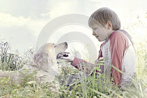 Young boy gently caresses his dog