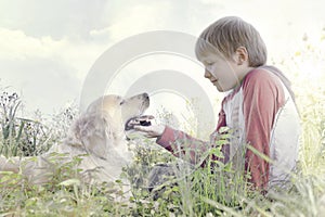 Young boy gently caresses his dog photo