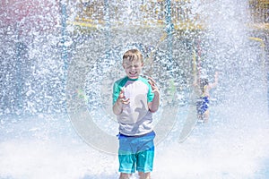 Young boy getting soaking wet while at an outdoor water park