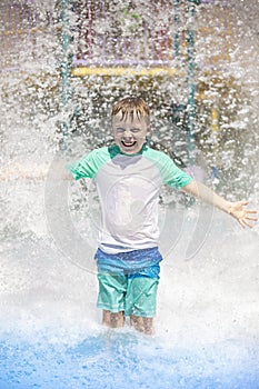 Young boy getting soaking wet while at an outdoor water park