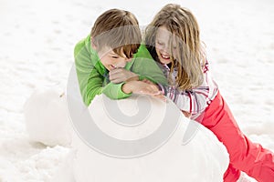 Young boy and girl building a snowman