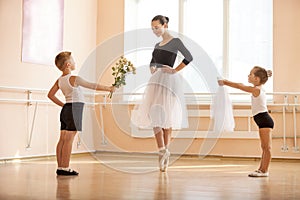 Young boy and girl giving flowers and veil to older student while she is dancing en pointe