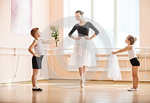 Young boy and girl giving flowers and veil to older student while she is dancing en pointe