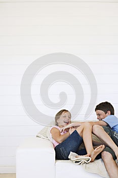 Young boy and girl laughing on couch in weatherboard room