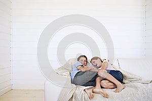 Young boy and girl laughing on couch in weatherboard room photo