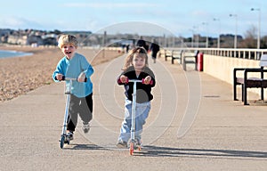 Young boy and girl playing on scooters photo