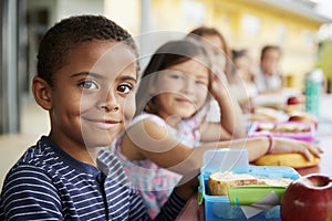 Young boy and girl at school lunch table smiling to camera photo