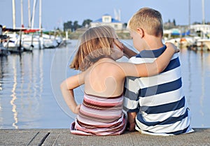 Young boy and girl sitting before water